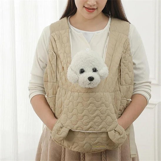 Une femme tient un sac de transport pur chien ventral, beige avec un chien en peluche blanc, doux, en train de regarder dehors.