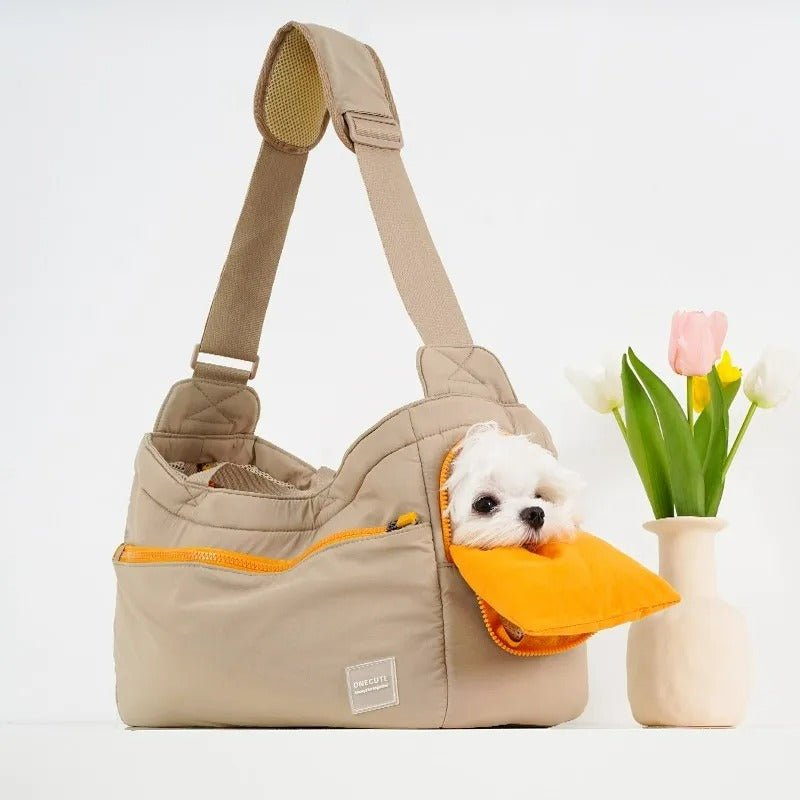  Un petit chien blanc sort d'un sac de transport polyvalent pour chien | coupe - vente kaki avec un rabat orange, à côté d'un vase de tulipes sur fond blanc.
